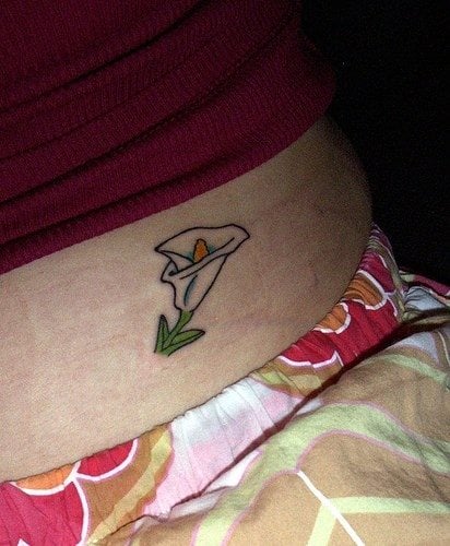 Pequeña flor de lis en la barriga de una chica joven.
