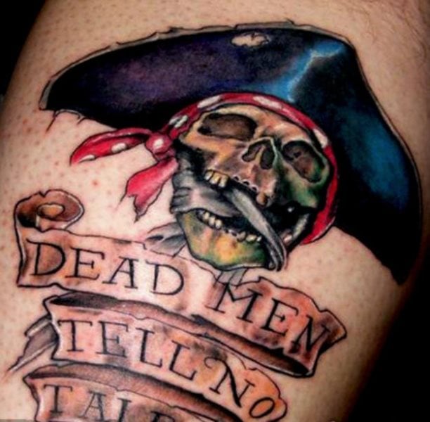 Tatuaje de letras grandes en inglés en la parte inferior y una calavera pirata con un pañuelo y un sombrero de pirata.