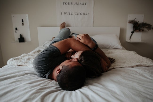 Una pareja se divierte y rie encima de una cama
