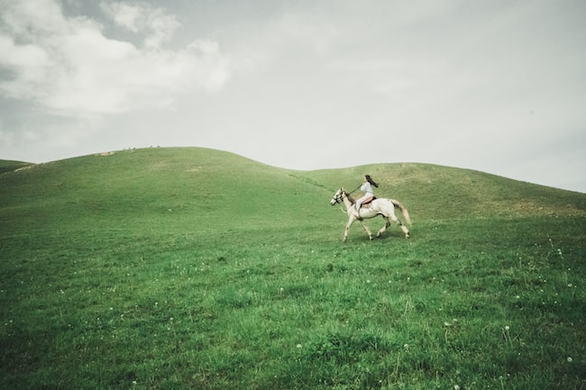 Una mujer montando un caballo blanco