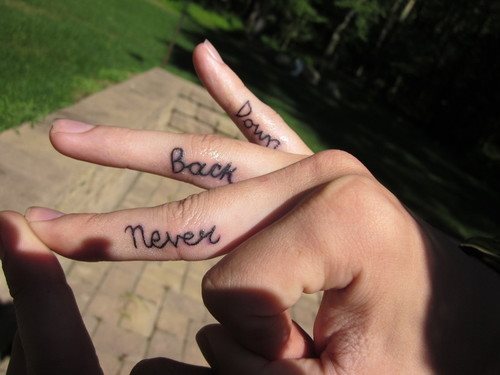 Tatuaje de frases entre los dedos de una mujer