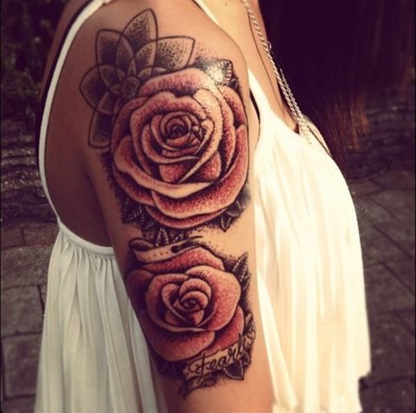  Tatuaje de grandes rosas en tonos rojos y negros en el brazo de una chica.