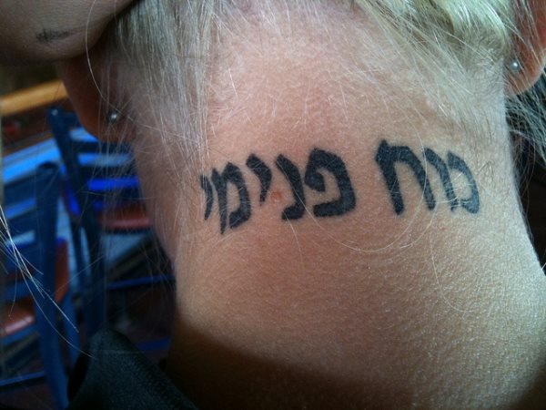 Tatuaje con letras hebreas debajo de la nuca