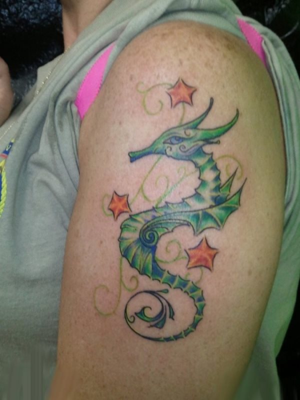 Tatuaje de un caballito de mar en tonos verdes rodeados de estrellas