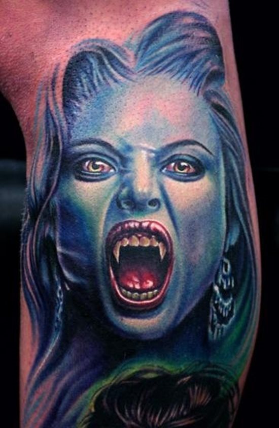 En esta imagen vemos el diseño de una mujer con grandes colmillos propios de un vampiro, la mujer tatuada se caracteriza por tener la piel en color azul, al igual que el pelo y unos ojos enrojecidos, cuyo iris es de color amarillo