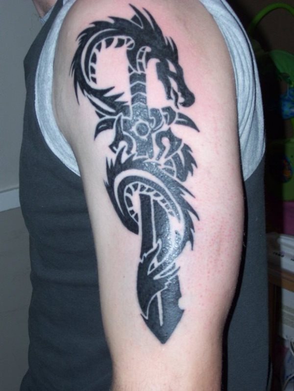 Tatuaje de una espada envuelta por un dragón con aires tribales y a color negro, tatuado sobre el brazo izquierdo