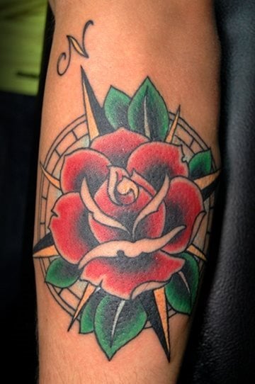 Una rosa en tonos rojos y verdes que parece estar situada encima de una brjula con sombreados que le dan algo de fondo al diseo, pero se trata de un tatuaje al que le falta algo de vida, quizs unos brillos blancos en contraste con los sombreados le hubieran proporcionado mayor personalidad al resultado final