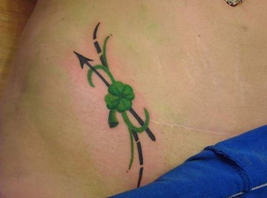 Trébol de cuatro hojas sobre el abdomen, en color verde y acopmpañado por una flecha recta negra que resaltan las líneas curvas del abdomen, sin duda es una buena elección para un tatuaje, si lo que estás busando es algo pequeño y un poco escondido