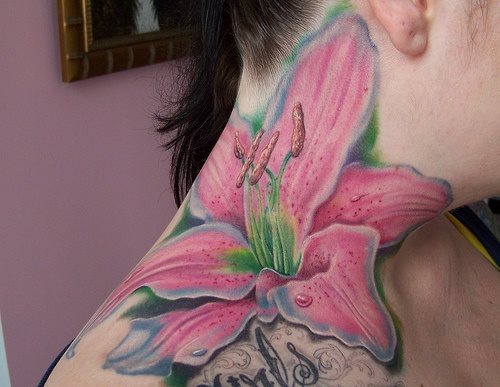 Esta chica ha optado por un tajuaje de gran tamao de un lirio rosa situado en su hombro, clavcula y cuello, y junto a lo que parece ser un tatuaje de tinta negra con temtica musical