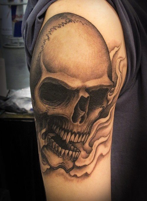 Una simple calavera con grandes colmillos tatuado sobre el brazo