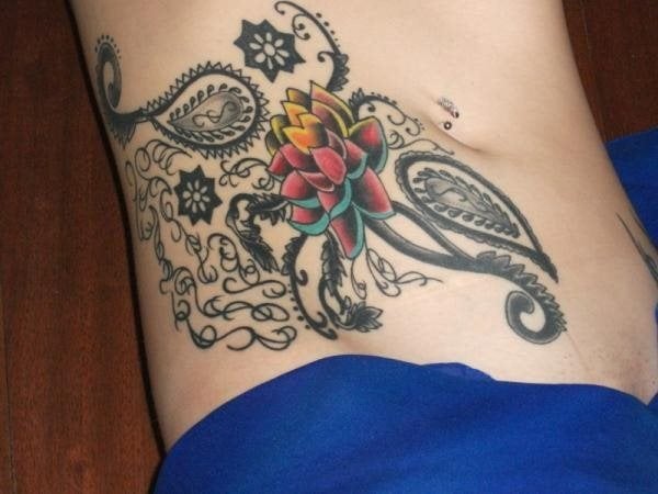 El siguiente tatuaje es un gran tatuaje de una flor, presumiblemente se trata de una flor de loto, a todo color, usando para ello comores como el amarillo, naranja, rojo y celeste