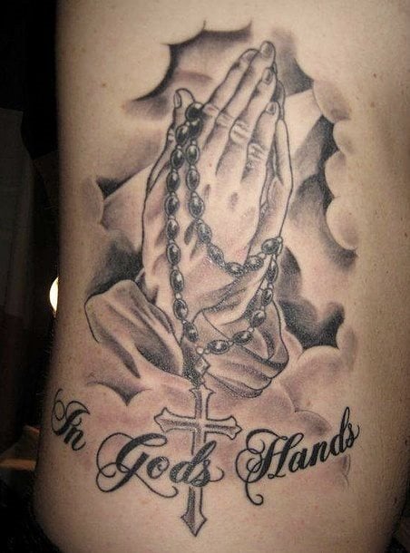 Diseo de dos manos rezando con un rosario y con una frase que dice In gods hands, que en castellano se traduce como En las manos de dios