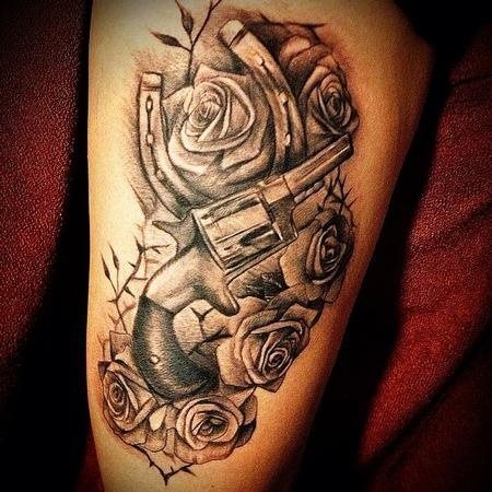 Pistola y herradura sobre un fondo de rosas