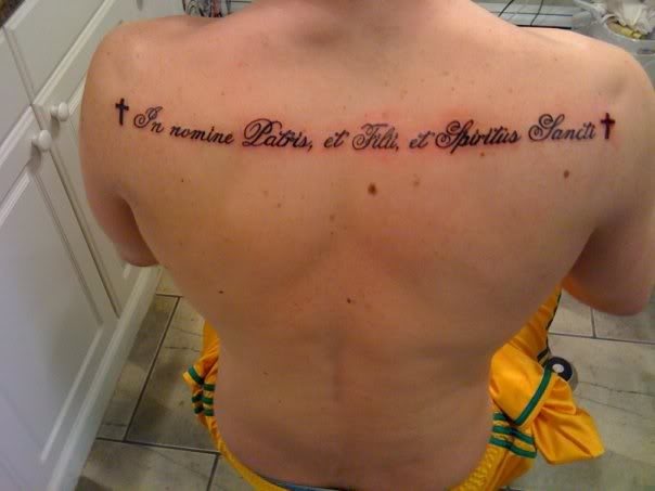 Tatuaje de una frase totalmente en horizontal ocupando toda la espalda de hombro a hombro y custodiada por una cruz a ambos lados del tatuaje, un tatuaje muy acertado para todas aquellas personas de grandes espaldas