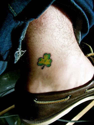 Pequeo trbol el que lleva este chico tatuado en el lateral del pie