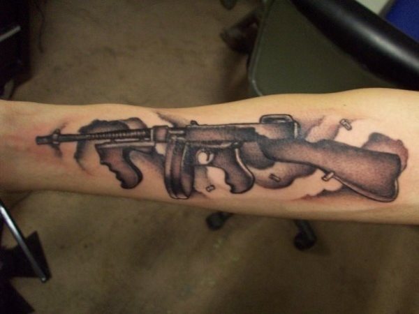 Rifle tatuado en la parte interna del brazo