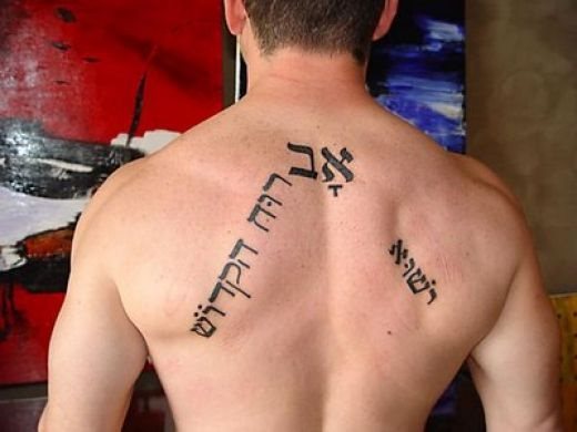 Tatuaje formando un triángulo sin base de unas frases en un lenguaje desconocido para nosotros, tal vez la gran complexión fuerte de este chico ayuda a que el tatuaje le quede bien, porque por sí solo, no nos dice demasiado