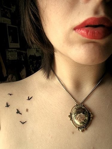 Tatuaje de uno pjaros volando en el hombro de esta chica, en tonos negros y tatuados a modo de detalle, ya que son pequeos y nicamente en un color negro