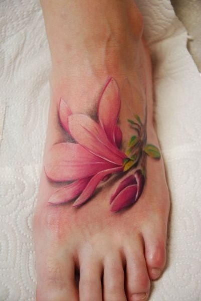 Elegante y realista tatuaje de una flor sensible a tonos pasteles, en el cual las sombras de color negra juegan un papel muy importante para darle ese realismo que parece quiere infundir el tatuaje, como podemos observar, estamos ante uno de los tatuajes en el empeine más elegantes que hemos visto, que hará las delicidas de cualquier mujer que ame los tatuajes