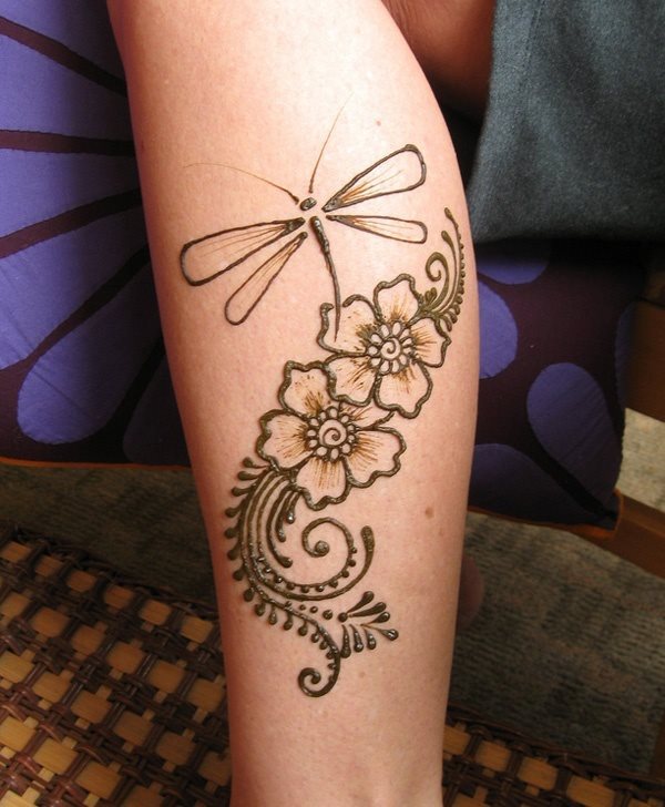 Tatuaje de henna de una libelula con un fondo de motivos florales