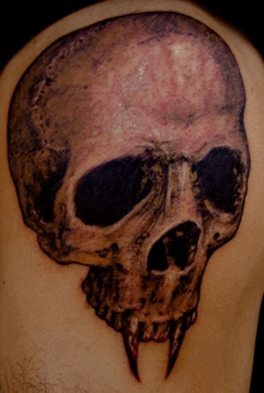 Tatuaje de una calavera vampírica en la que se puede apreciar un enorme craneo con dos colmillos muy marcados
