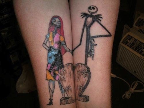 Tatuaje de pareja en el que uno de ellos tiene tatuado una especie de momia hombre y ella una mujer de vestido colorido, bajo el tattoo se ha realizado un tatuaje de corazón de piedra que para que se vea completo deben unir las dos personas sus brazos