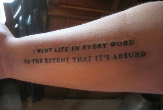 Tatuaje en el antebrazo de una frase en letras mayúsculas que dice I Want life in every word to the extent that it´s absurd