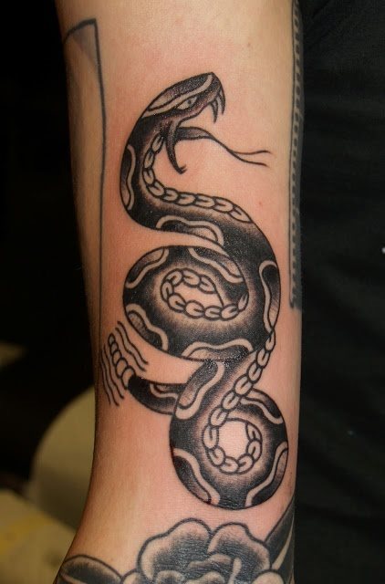 Tatuaje negro de una serpiente con la boca abierta y sacando su lengua bífida, con una postura bastante expresiva y que nosotros hubiéramos dejado como está, pero incluyendo algunos colores para dotar de algo más de personalidad a este tattoo