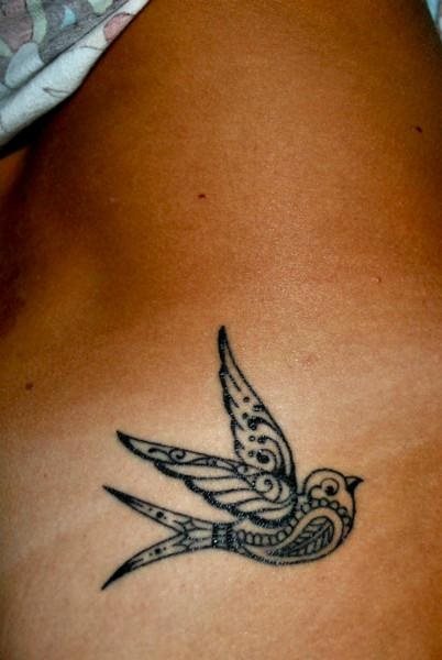 Tatuaje de una golondrina en color negro con un relleno de dibujos preciosos y unos acabados que nos encantan, la verdad es que estamos ante uno de los tattoos de golondrinas de los que más nos gustan de toda la galería