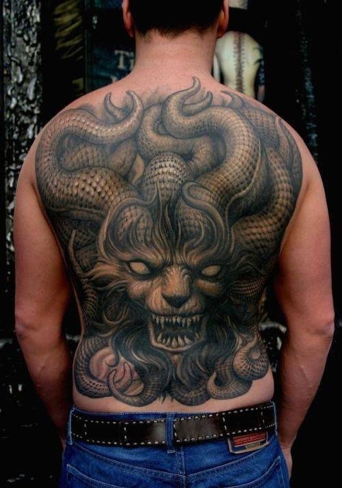 Enorme tatuaje en color negro que ocupa toda la espalda de este hombre y en el que se aprecia un enorme dragón con más cuernos que un puesto de caracoles y en el que se destacan lo bien terminado que están los cuernos y del que nos gusta la cara peluda con la que se ha caracterizado a este ser, no es un tatuaje que pasa desapercibido ya sea por su gran tamaño o por lo bien rematado de los detalles por parte de la persona que ha realizado el tatuaje