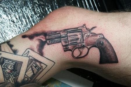 Una pequea pistola y varias caratas de pker componen este tatuaje en el lateral de la pierna