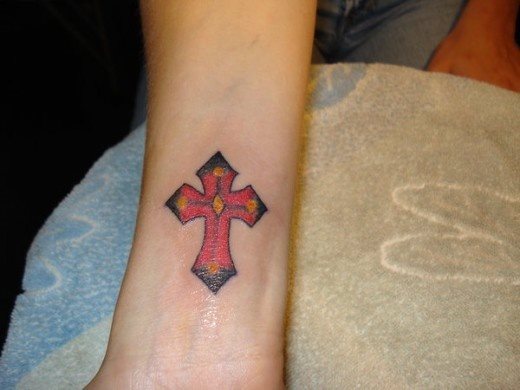 Cruz roja o negra tatuada en el antebrazo de un chico muy religioso