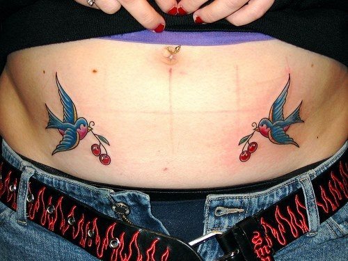 Dos golondrinas simtricas tatuadas en ambos lados del abdomen que llevan unas cerezas en sus picos