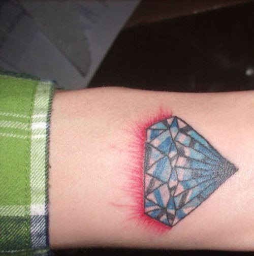 Tatuaje algo extrao que combina la imagen de un diamanete (algo irregular y con un trazado poco recto) con una sombra roja a modo de destello