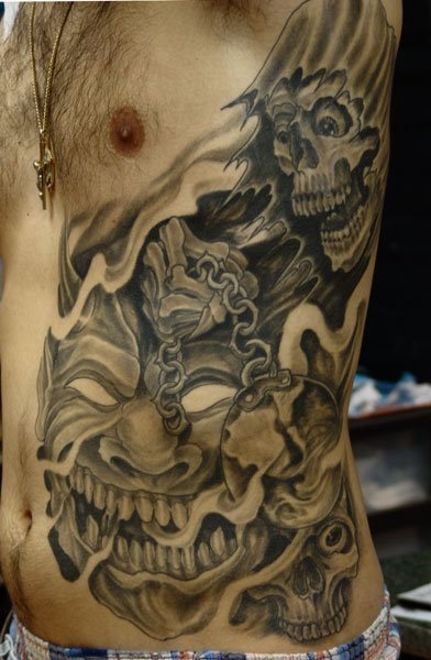 Calavera que representa la muerte y otras caras al fondo ocupan todo el costado de este hombre tatuado, nos llama la atención como las calaveras están encadenadas y la sensación de terror y miedo que infunde este tatuaje, que creemos también hubiera quedado muy terrorífico e impactante si para su elaboración se hubieran utilizado más colores aparte del negro