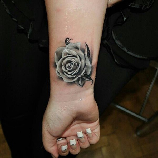 Imagen de una rosa blanca y con sombreados negros tatuada en la mueca