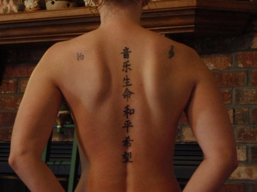Esta chica exhibe este bonito tatuaje de una lnea vertical de caracteres chinos a lo largo de la lnea de su columna vertebral, para el que se ha usado simplemente tinta negra