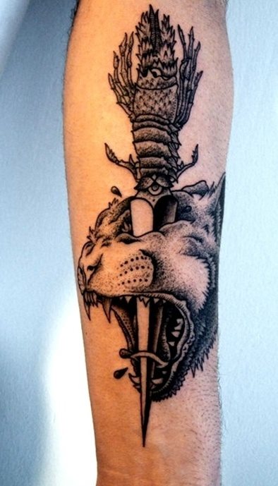 Tatuaje en el brazo de un len con una daga clavada en el ojo