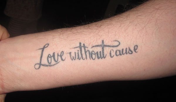 Tatuaje en el antebrazo con unas finas letras que describen la frase Love without cause, un tatuaje para enamorados de verdad