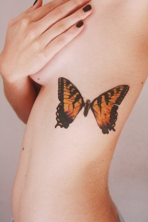 Tatuaje muy sexy de una mariposa de tamaño considerable en el que sólo se han utilizado los colores negros y naranjas, dándole un aspecto atigrado que nos gusta mucho, al igual que toda la fotografía al completo