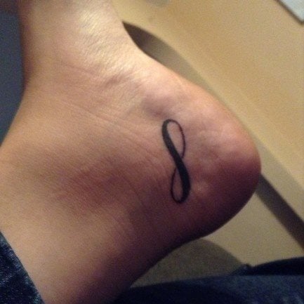 Sencillo tatuaje del símbolo de infinito en una parte del cuerpo que no se ve con facilidad