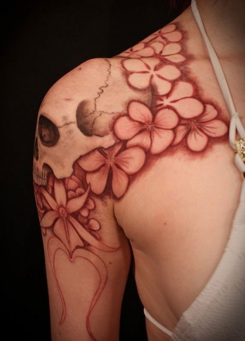 Calavera tatuada en el hombro y rodeada de flores