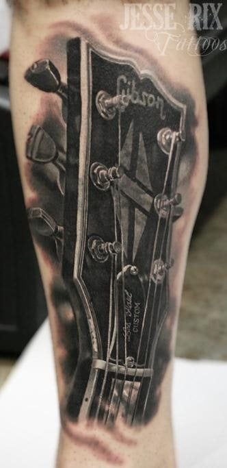 Tatuaje de una guitarra en la que sólo se ha tatuado la cabeza con todos los detalles, las clavijas, cuerdas, etc