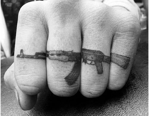 Esta persona se ha tatuado un rifle a lo largo de los dedos de la mano