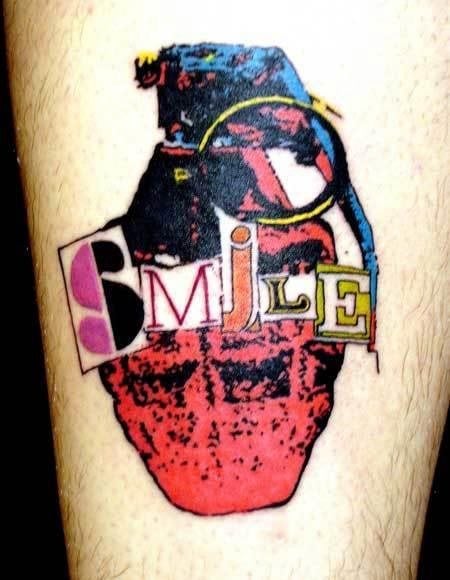 Tatuaje de una granada con colores tipo pop art en cuyo centro se ha tatuado la palabra smile con distintas tipografías, colores y formas