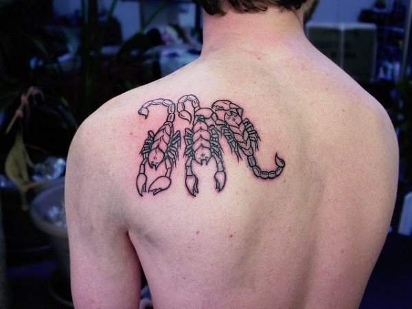Tres similares escorpiones tatuados en la parte izquierda de la espalda de este joven hombre
