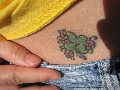 Pequeo trbol de cuatro hojas sobre el abdomen rodeado de diminutas flores