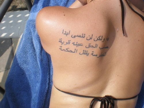 Tatuaje en el omóplato de una frase escrita en idioma árabe y para el que se ha dejado un gran espacio entre línea y línea, para así facilitar su lectura a todos los que entiendan este idioma, nosotros no lo conocemos