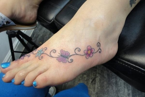 Enredadera con florecillas y mariposas conforman este delicado tatuaje que muestra la delicadeza que muchas personas eligen para dejan constancia sobre su piel de tinta para el resto de tu vida