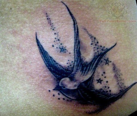 Tatauje de una golondrina en tonos azulados y para la que se han tatuado unos puntos y pequeñas alrededor del pájaro